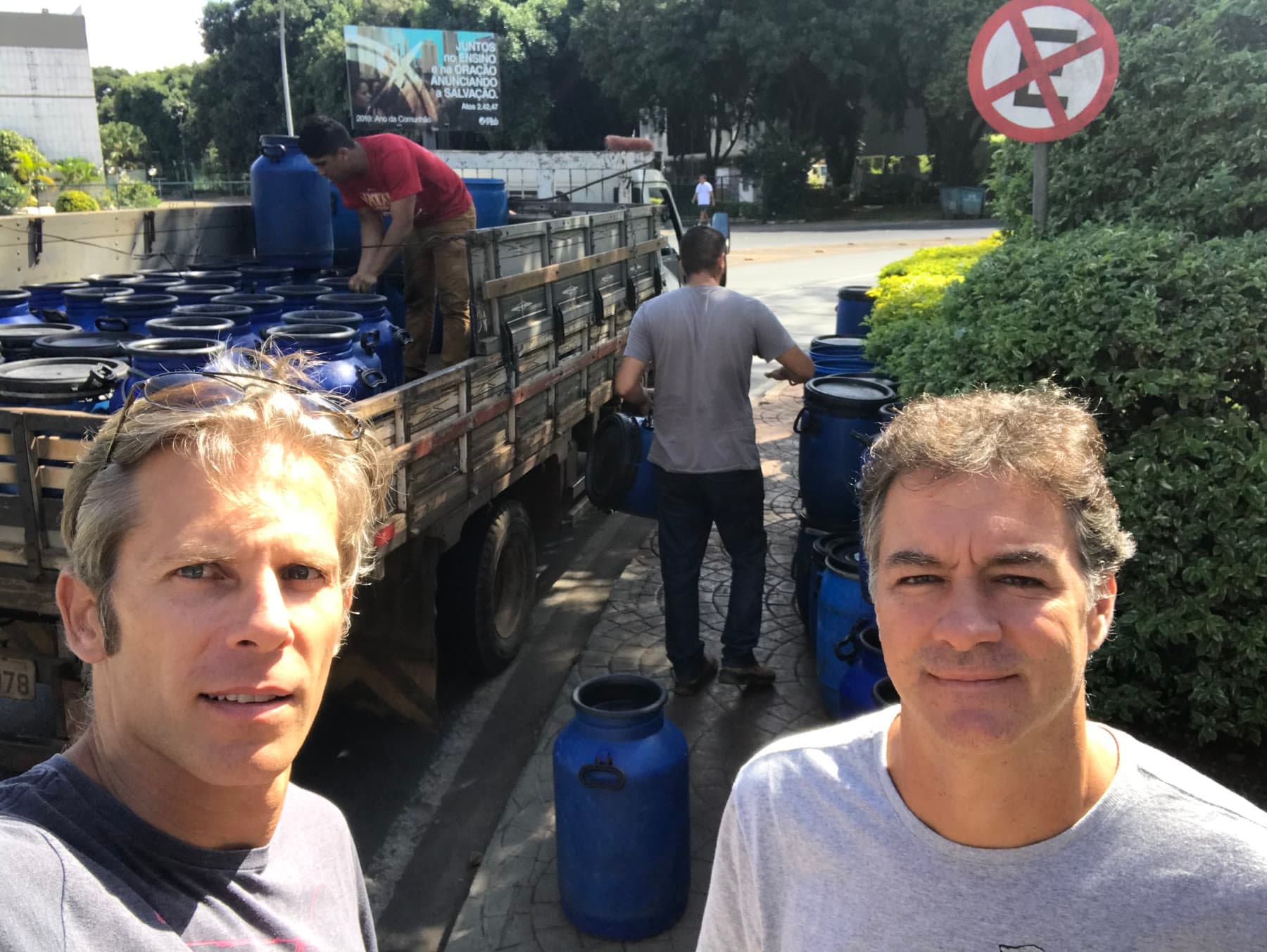 Ian e Marcelo ao lado de um caminhão carregado com bombonas de coleta