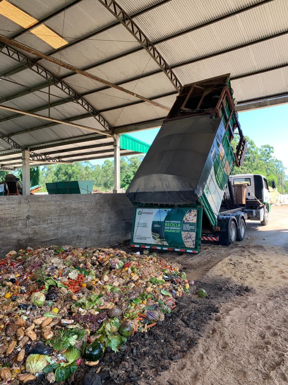 Um caminhão da Composul descarregando uma carga de orgânicos separados; o caminhão e a carga aparecem por inteiro.